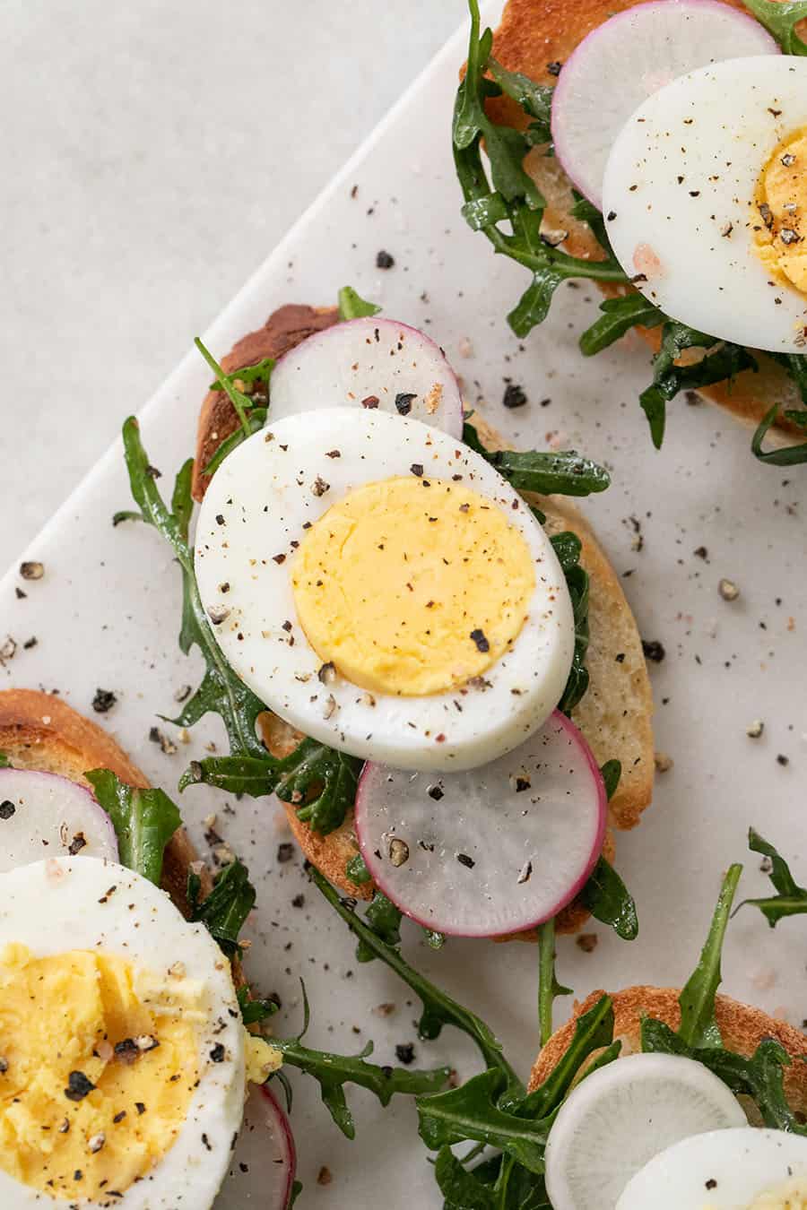 hard boiled egg, sliced on a crostini with salt and pepper and radish