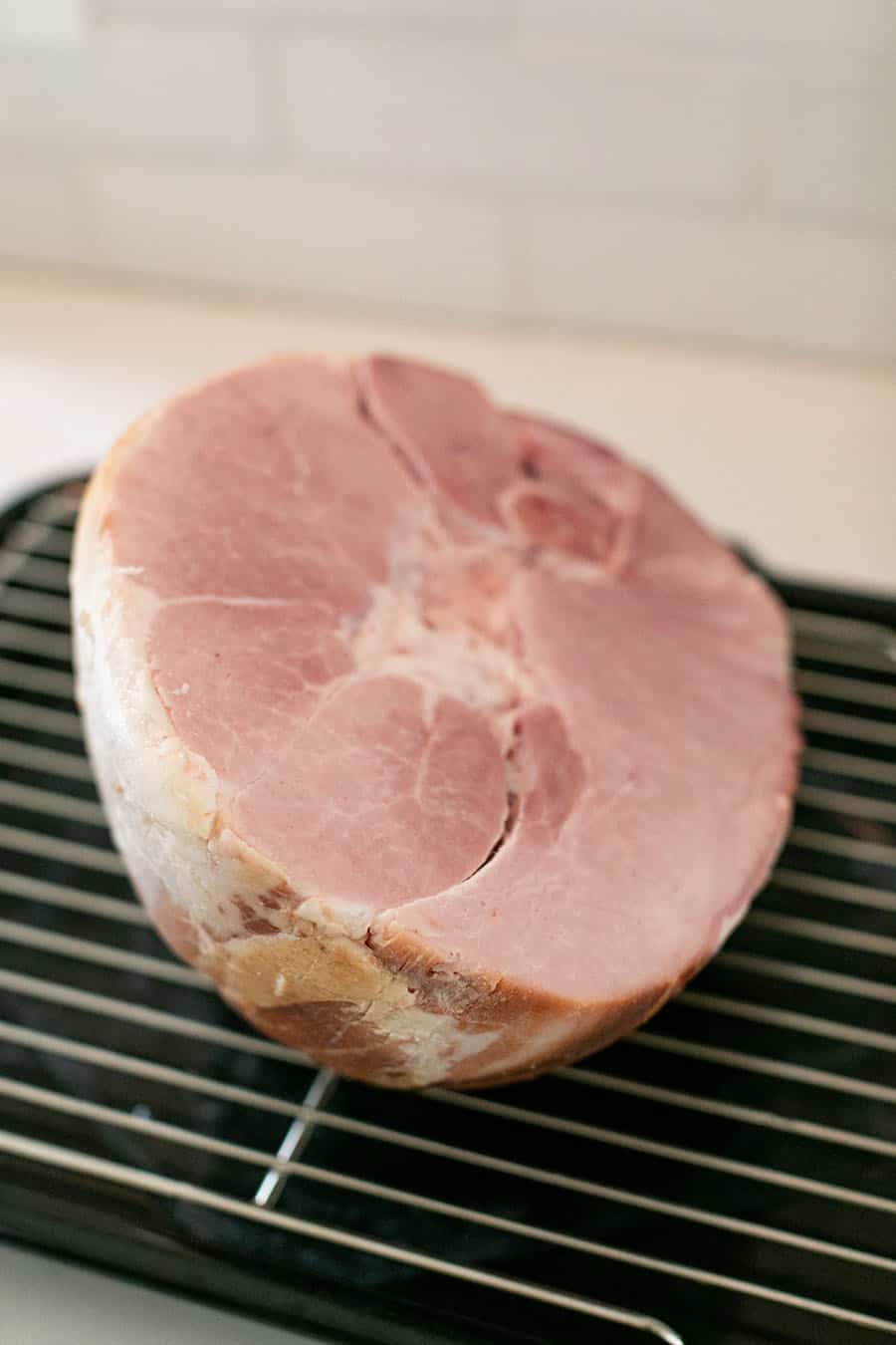 A cooked ham on a roasting rack before it goes in the oven.