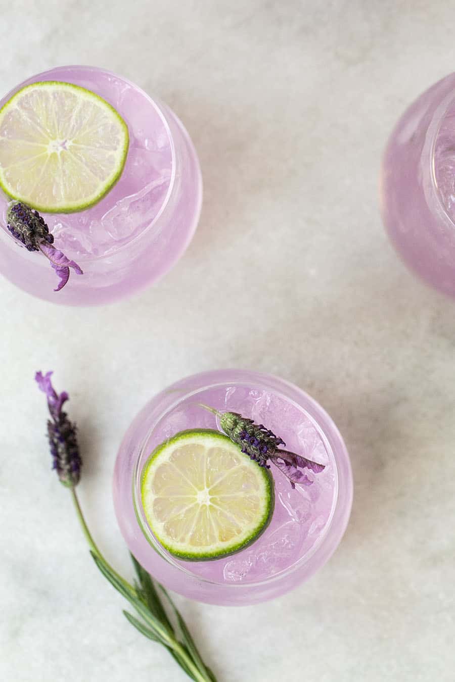 Purple ginned tonic punch with a lime slice on a marble table.