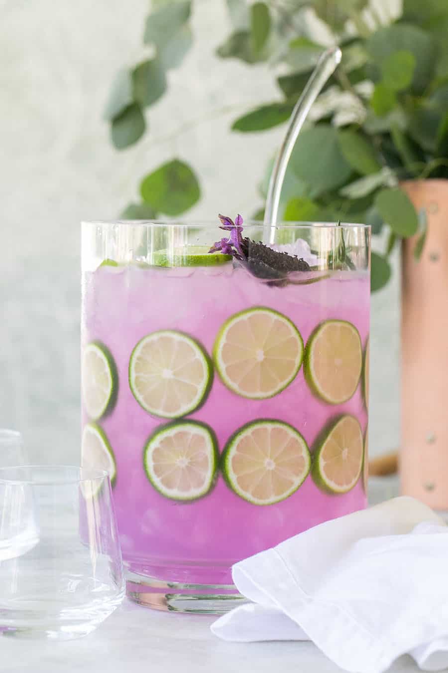 Lavender gin and tonic in large pitcher with lime slices