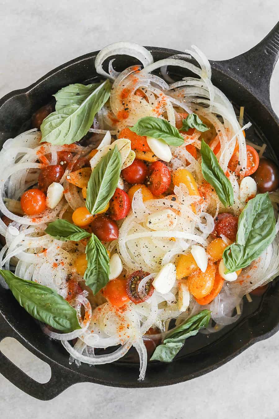 Pasta ingredients in a cast iron pan with garlic, tomatoes, basil, onions and noodles. - tomato basil pasta