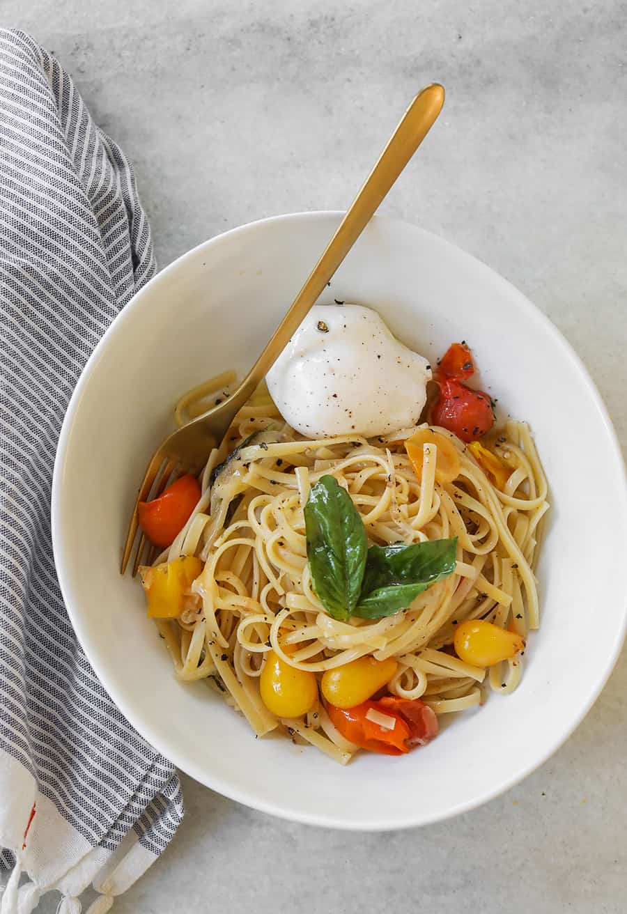 One Pan Basil and Tomato Pasta in a bowl with basil and tomatoes 