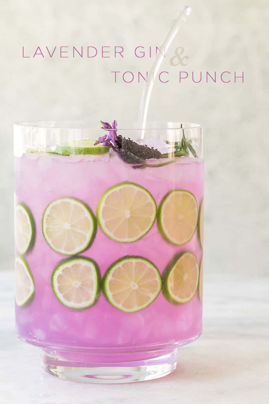 Purple gin and tonic punch with lime slices in a punch bowl.