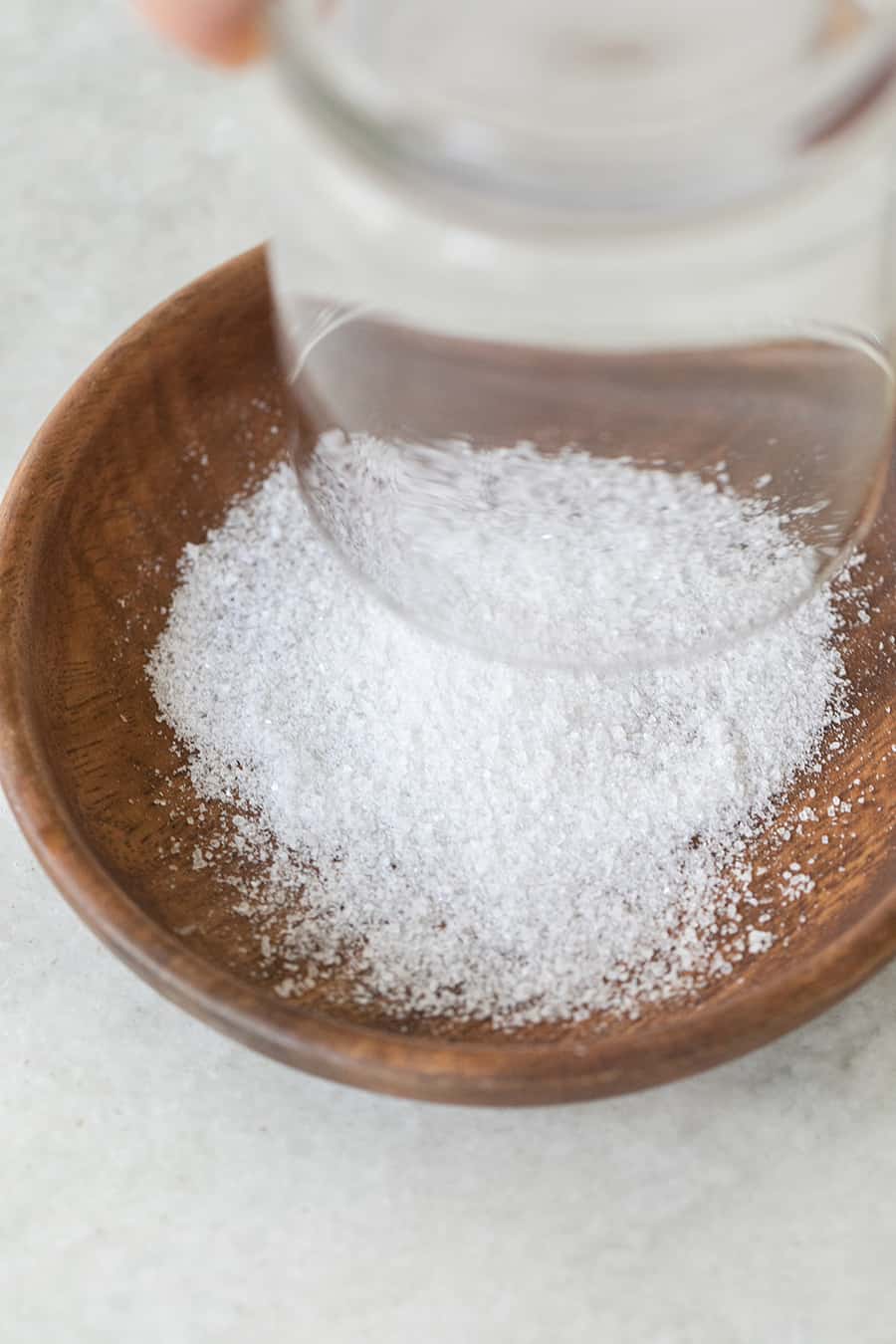 Rimming a glass with rock salt in a wooden bowl.