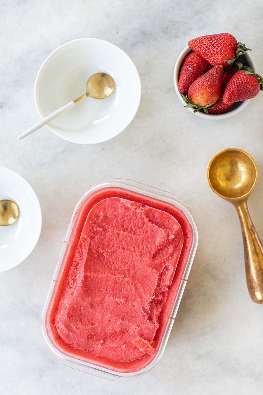 Elderflower strawberry sorbet with a gold ice cream scooper.