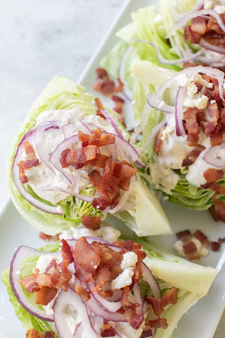 The most delicious wedge salad recipe ever with bacon, onions and dressing!