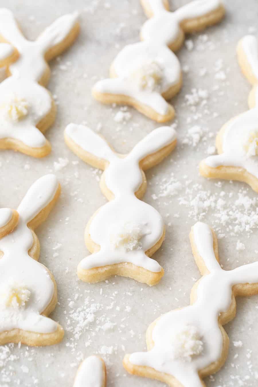 Easter cookies shaped as bunnies, frosting with white royal icing and a buttercream tail sprinkled with coconut.