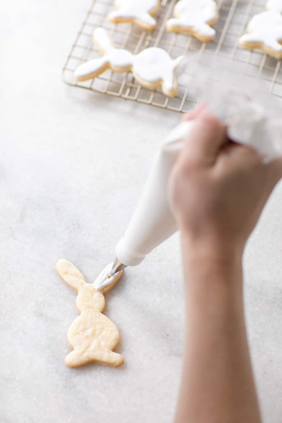 Hand frosting a bunny shaped Easter cookie.