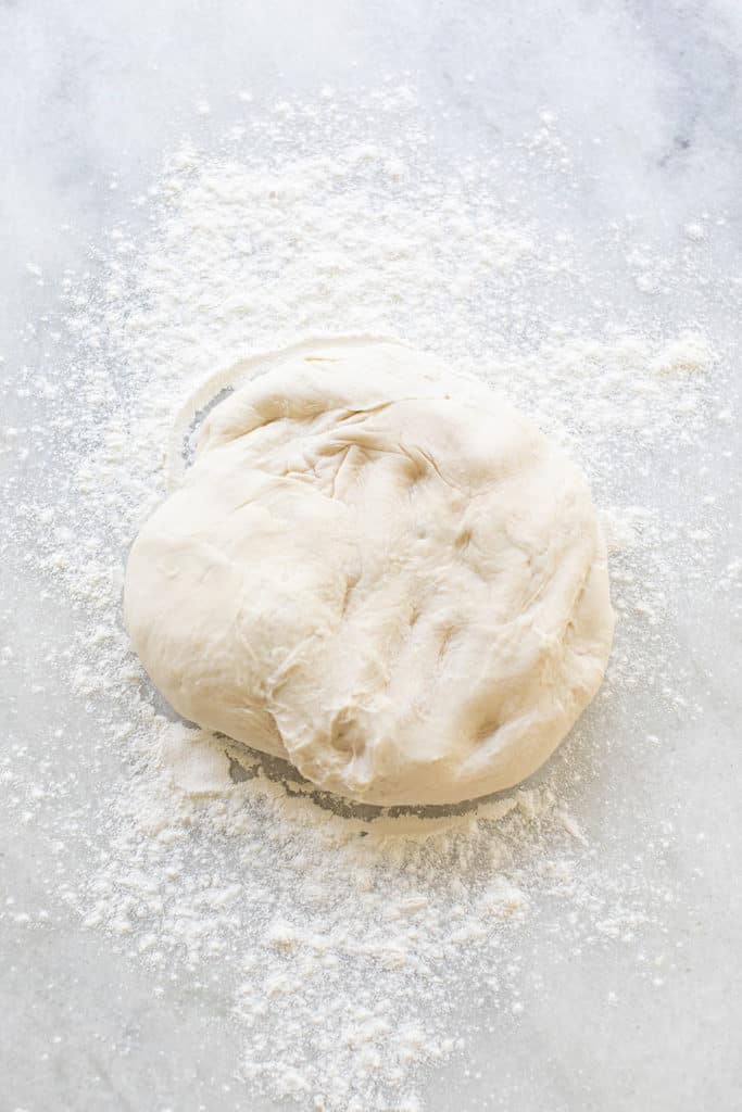 Ball of dough with flour getting ready to be rolled out for cinnamon rolls.