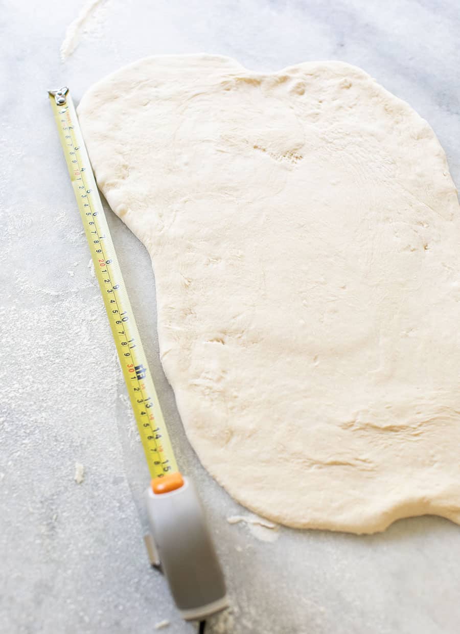 Measuring bread dough to make cinnamon rolls.