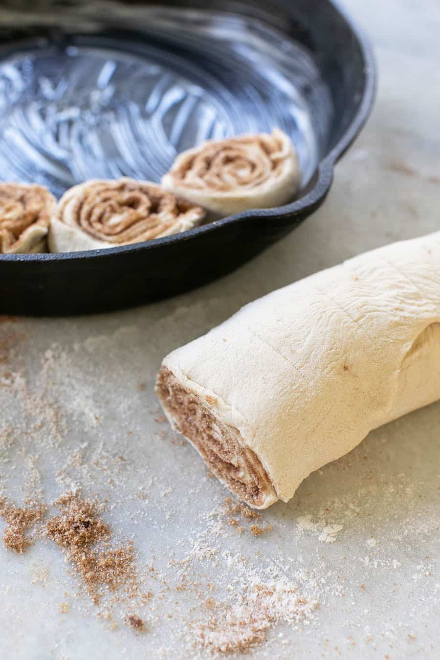 Rolling up a cinnamon roll to put into a pan to bake.