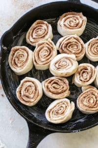 Cinnamon rolls in a cast iron skillet before they bake in the oven.