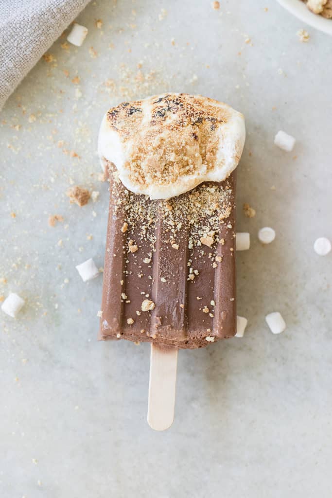 Chocolate own homemade popsicles with marshmallow topping and graham cracker crumble on a marble table. - popsicle mold