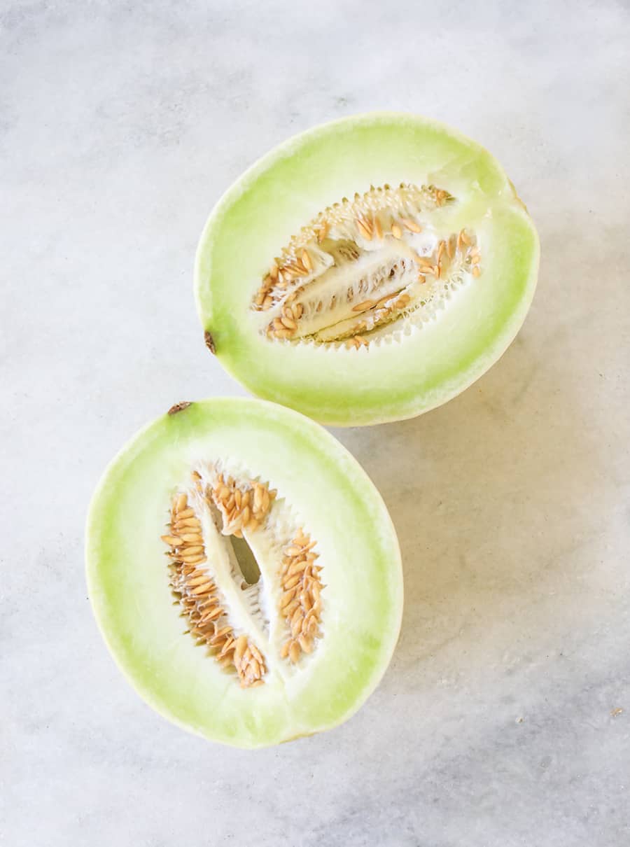 Honeydew cut in half on a marble table.