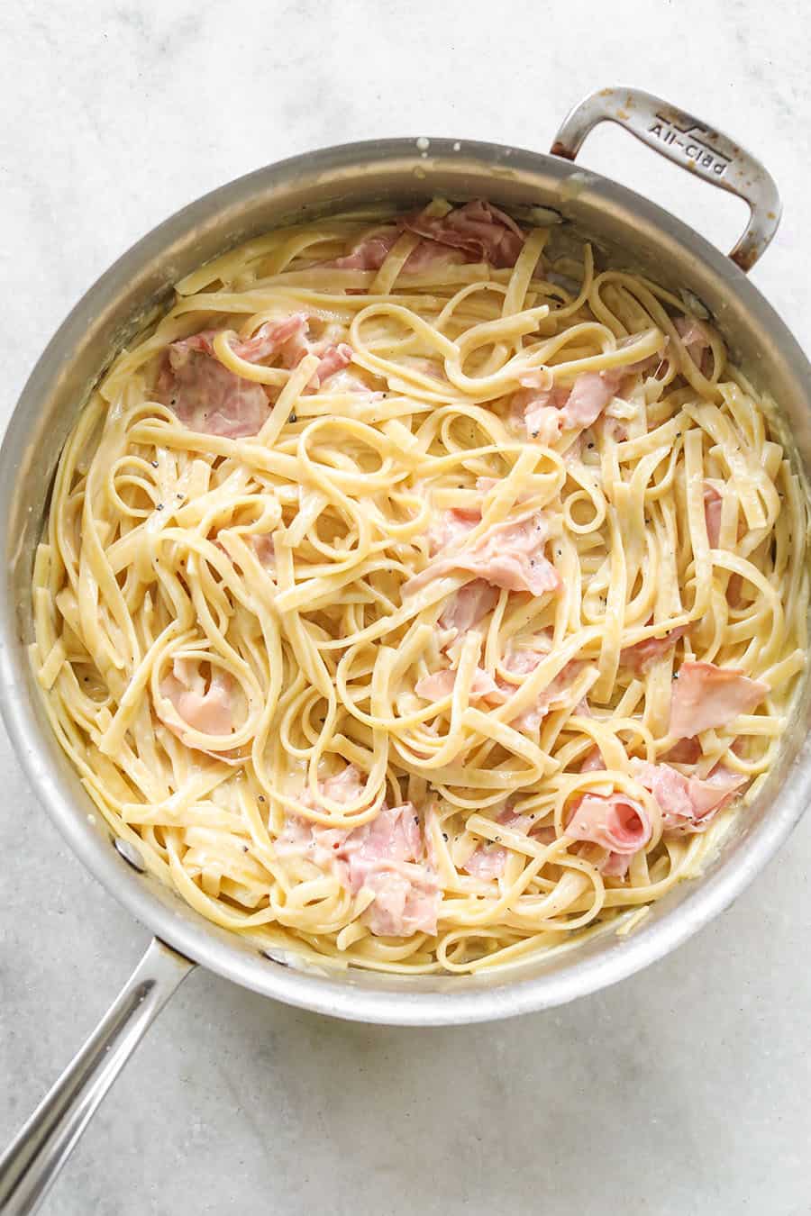 One Pan Fettuccine with Prosciutto in skillet on marble table. 