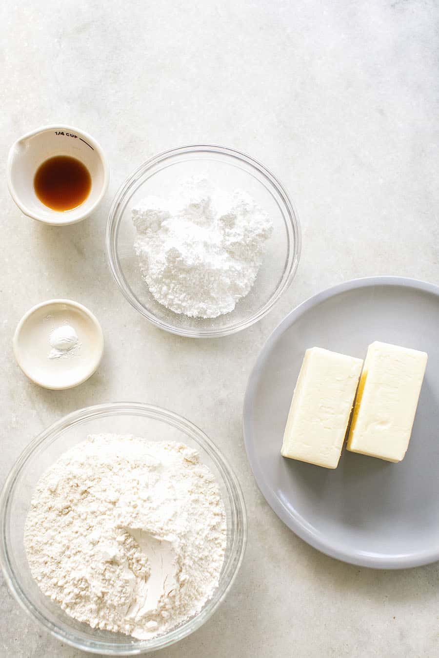 Flour, sugar, two sticks butter, vanilla extract baking powder on a marble table