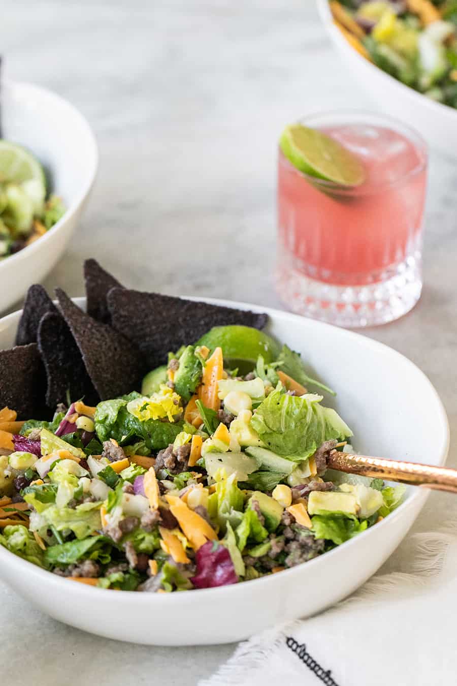 Taco salad bowl with blue chips and margaritas. 