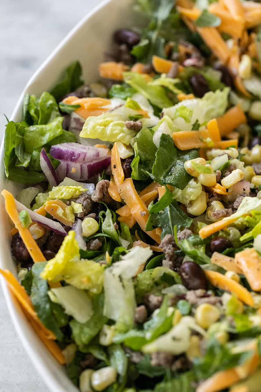 close-up of taco salad with beans, onions, corn, cheese and more 
