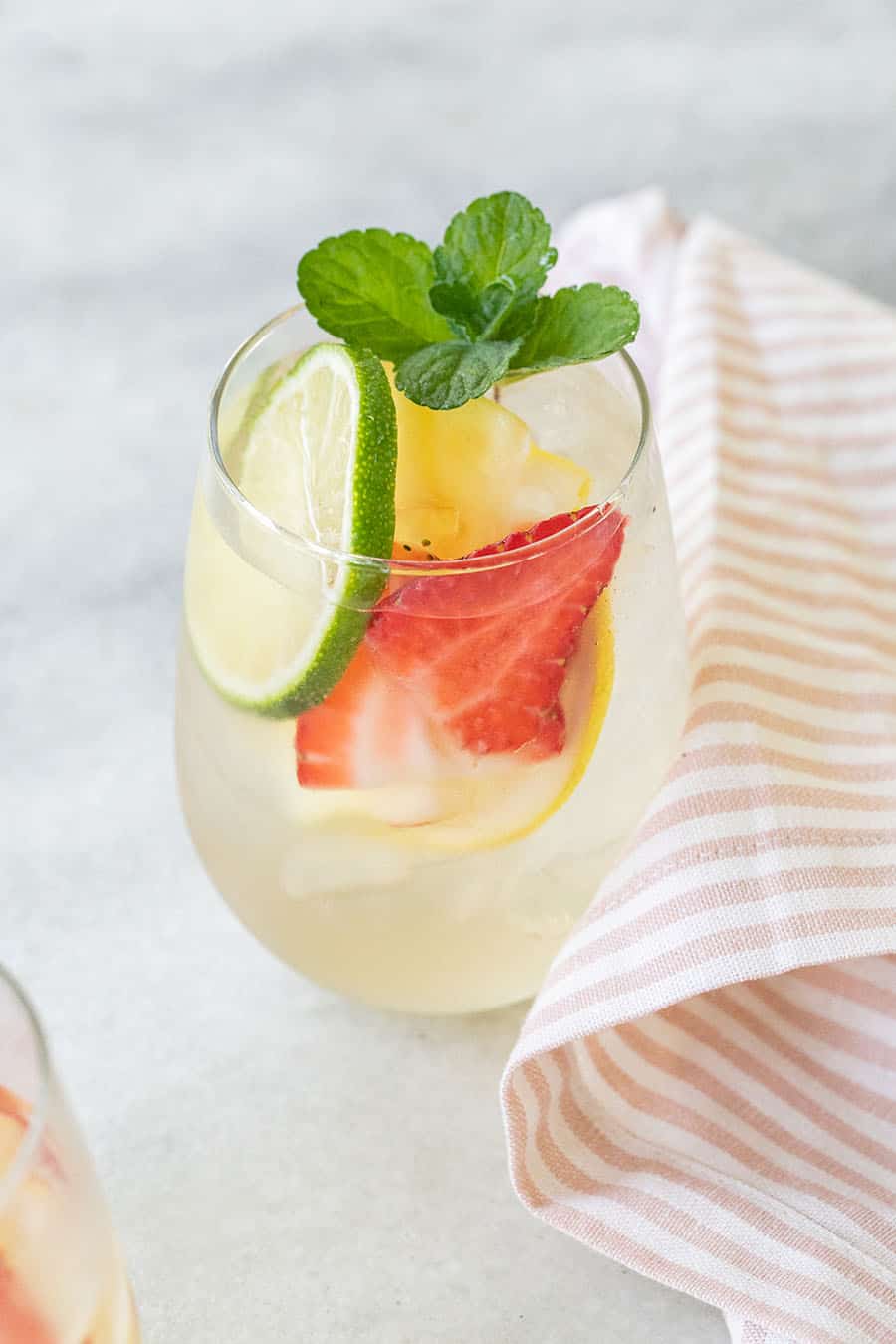 A glass of white wine sangria with strawberries, limes, lemons, apple vodka and pear liqueur.