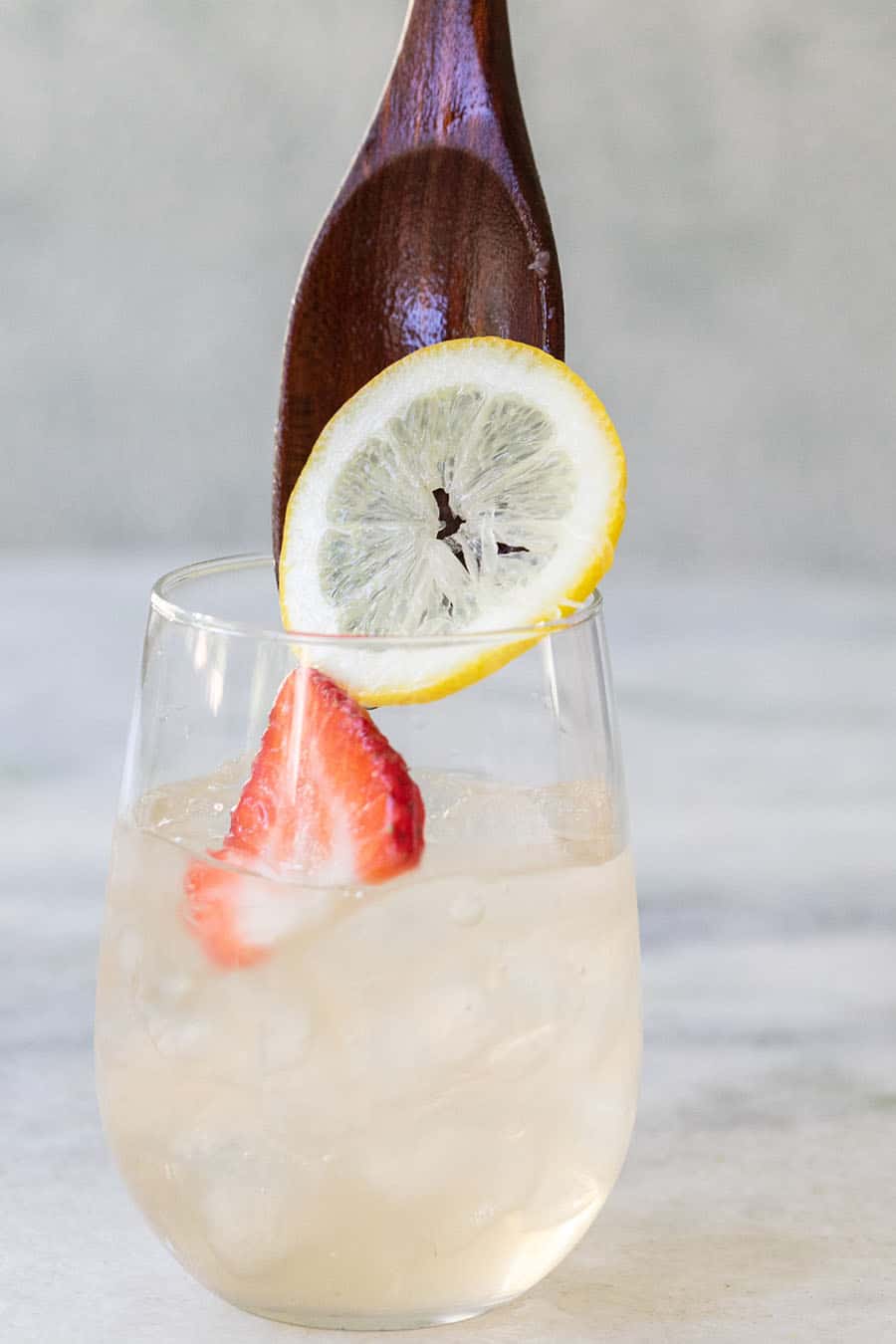 Wooden spoon dropping in ingredients for a white wine sangria.