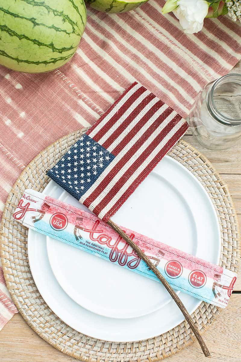 White plates on woven charger with burlap flags and large old-fashioned taffy. 