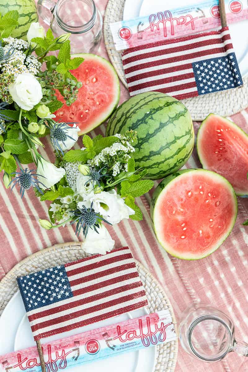 4th of July party table setting with flowers, watermelon, burlap flag and taffy.