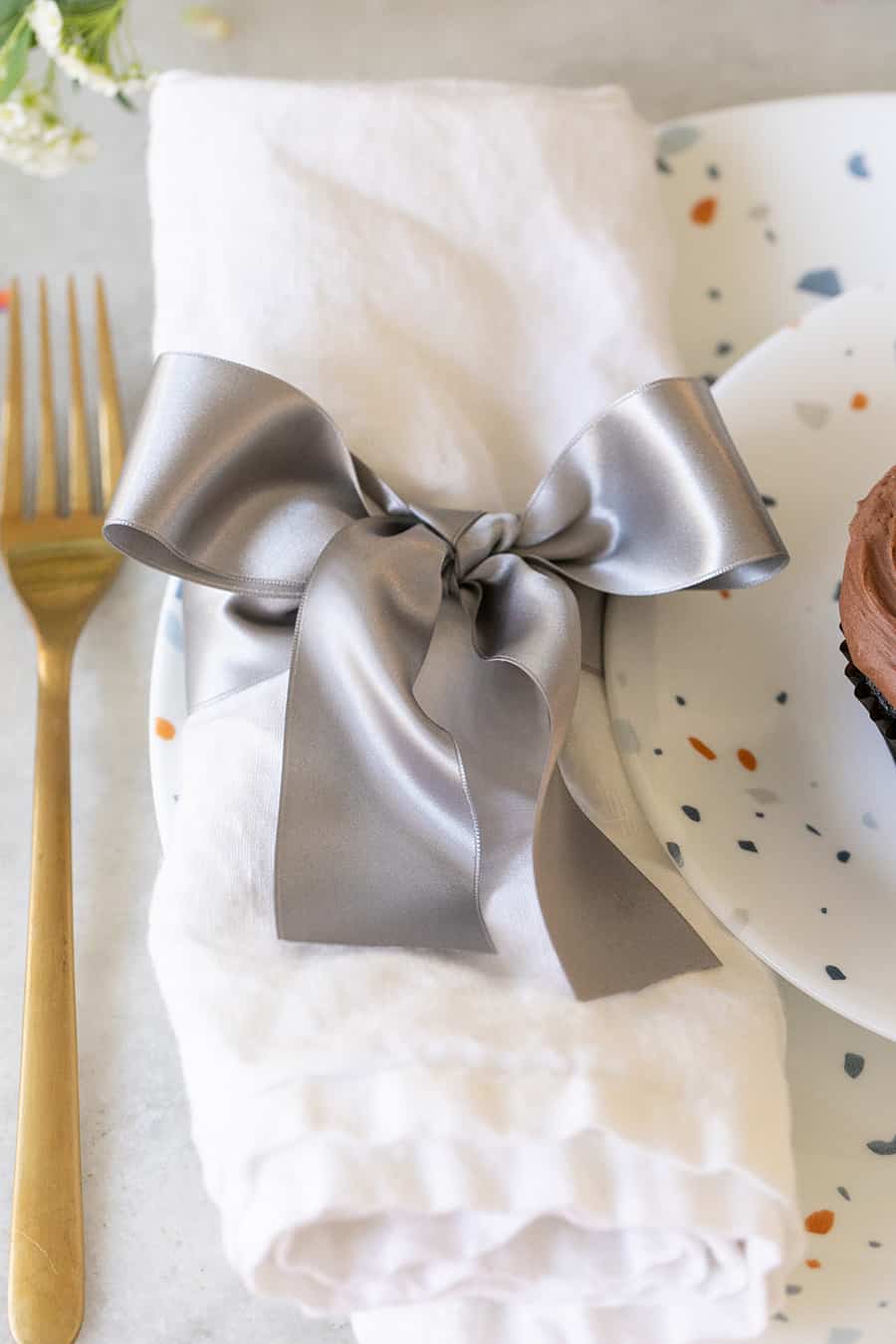 White napkin with a silver ribbon tied around it.