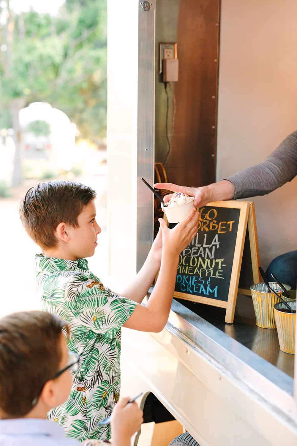 Serving kids ice cream from ice cream truck at a tropical summer party.