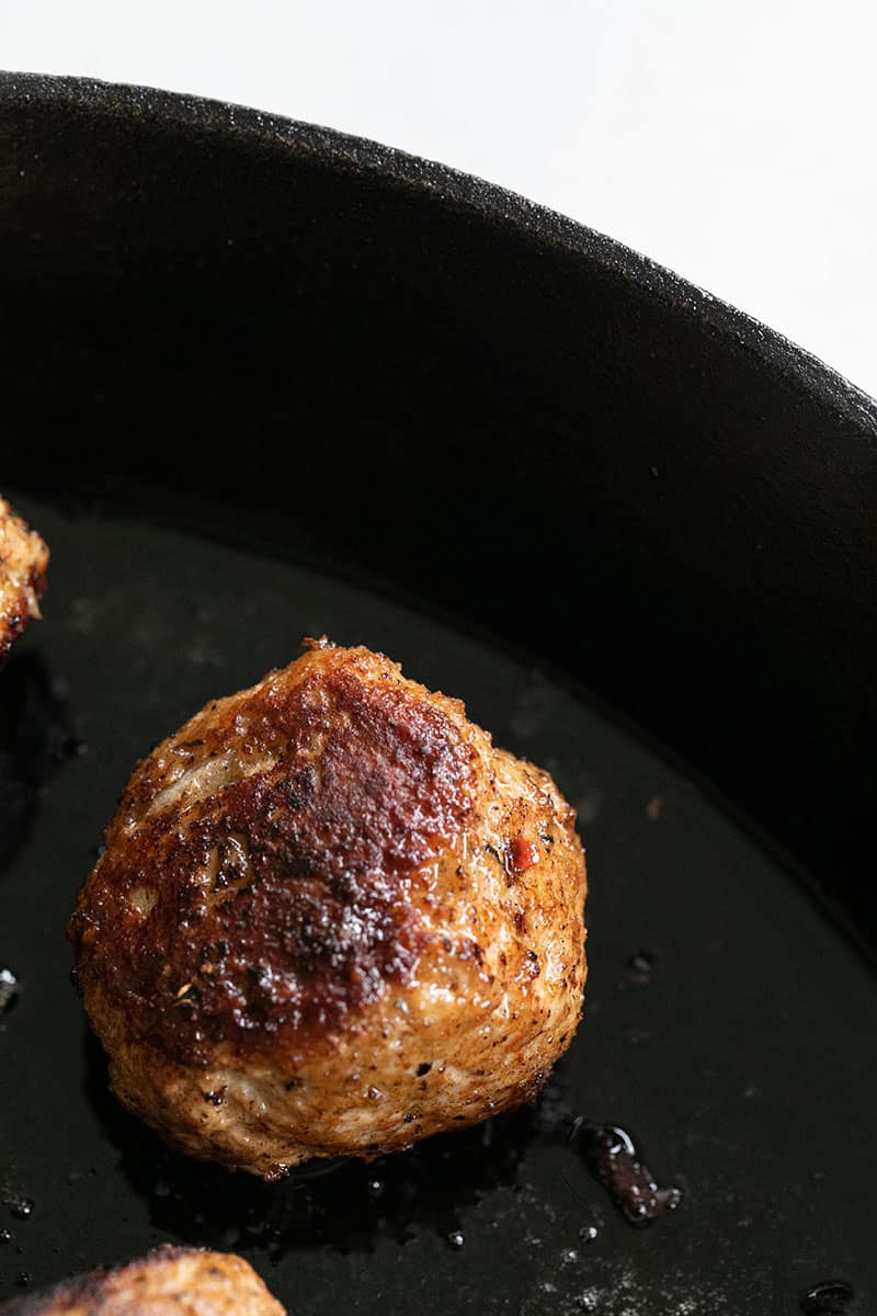 Golden brown turkey meatball in cast iron pan. 