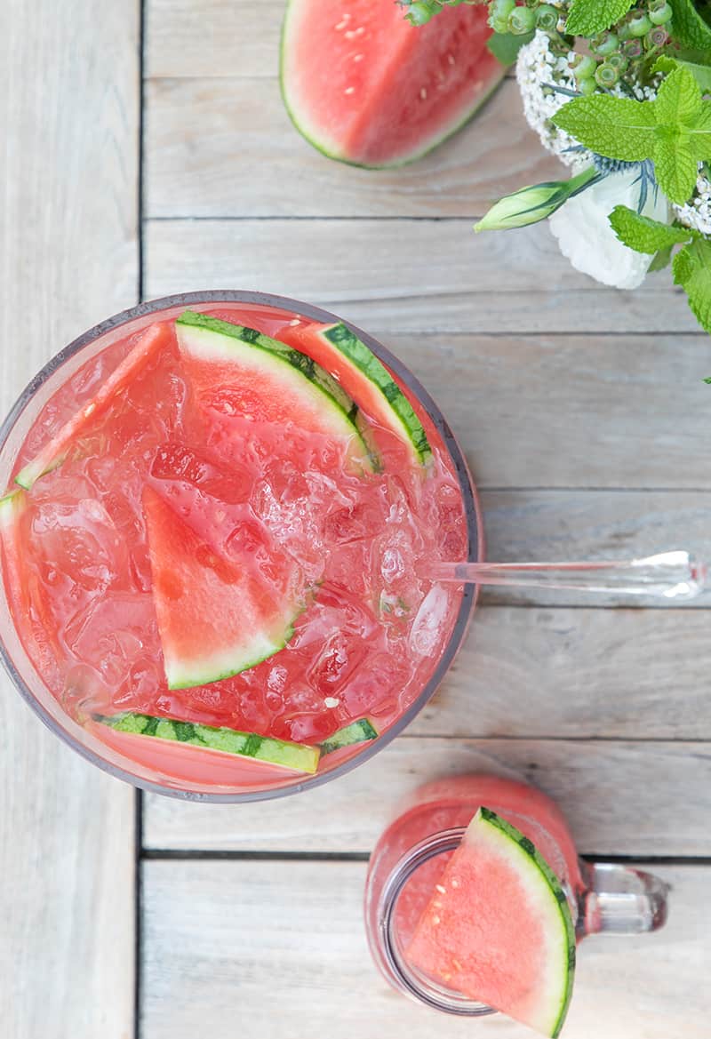 Watermelon punch with slices of watermelon on an outdoor table.