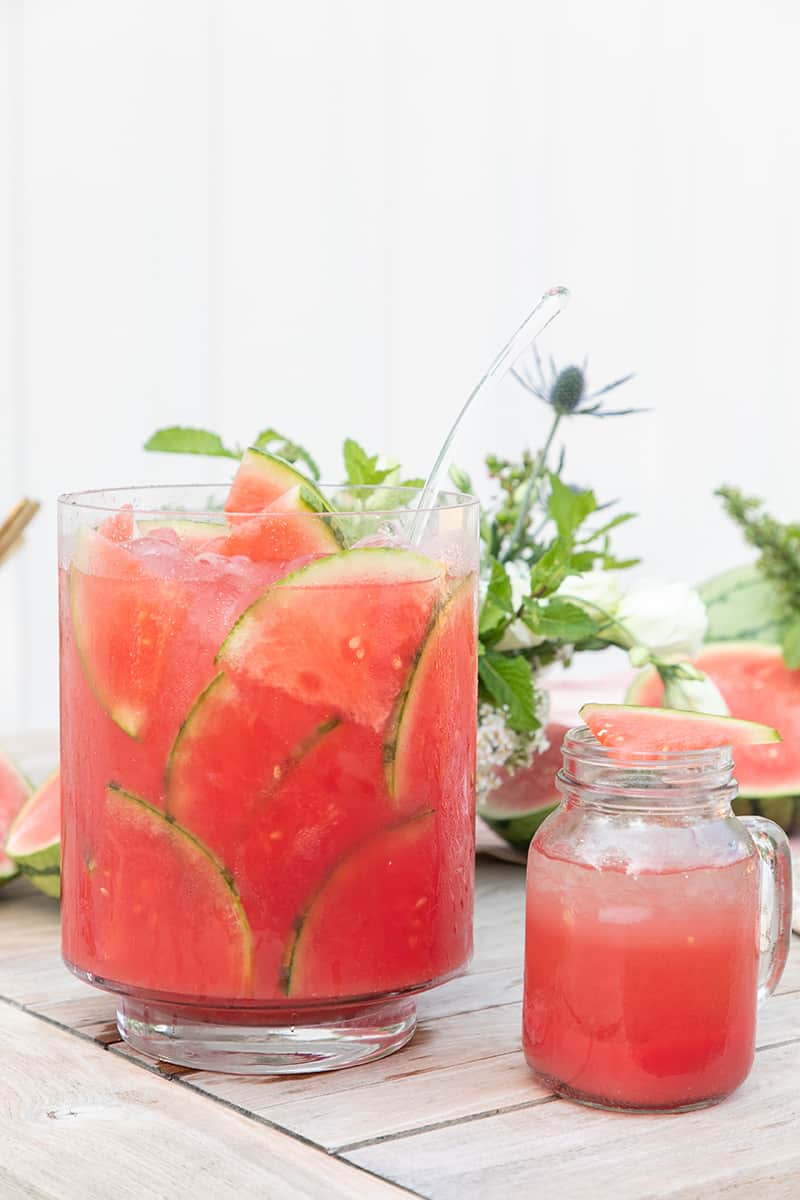 Watermelon punch in large glass pitcher with watermelon slices.