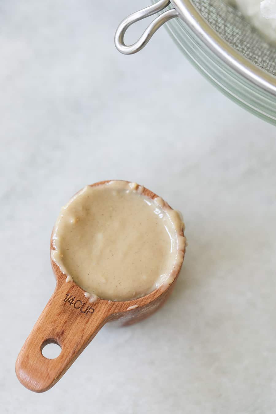 Tahini in a 1/4 wooden measuring cup. 