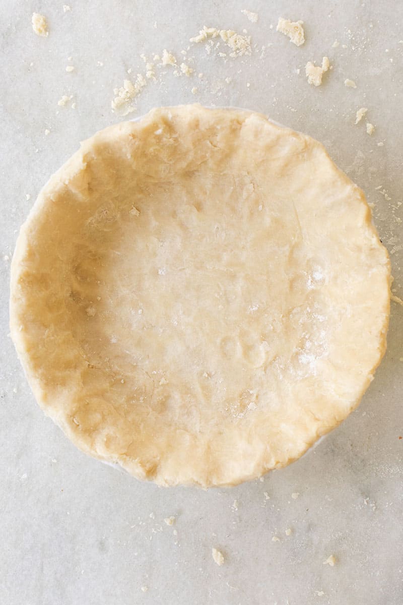 overhead photo of a pie crust on marble table.