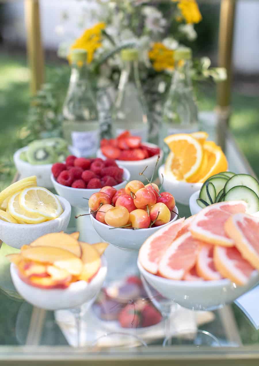 Cherries, apples, grapefruit in small bowls on gold bar cart