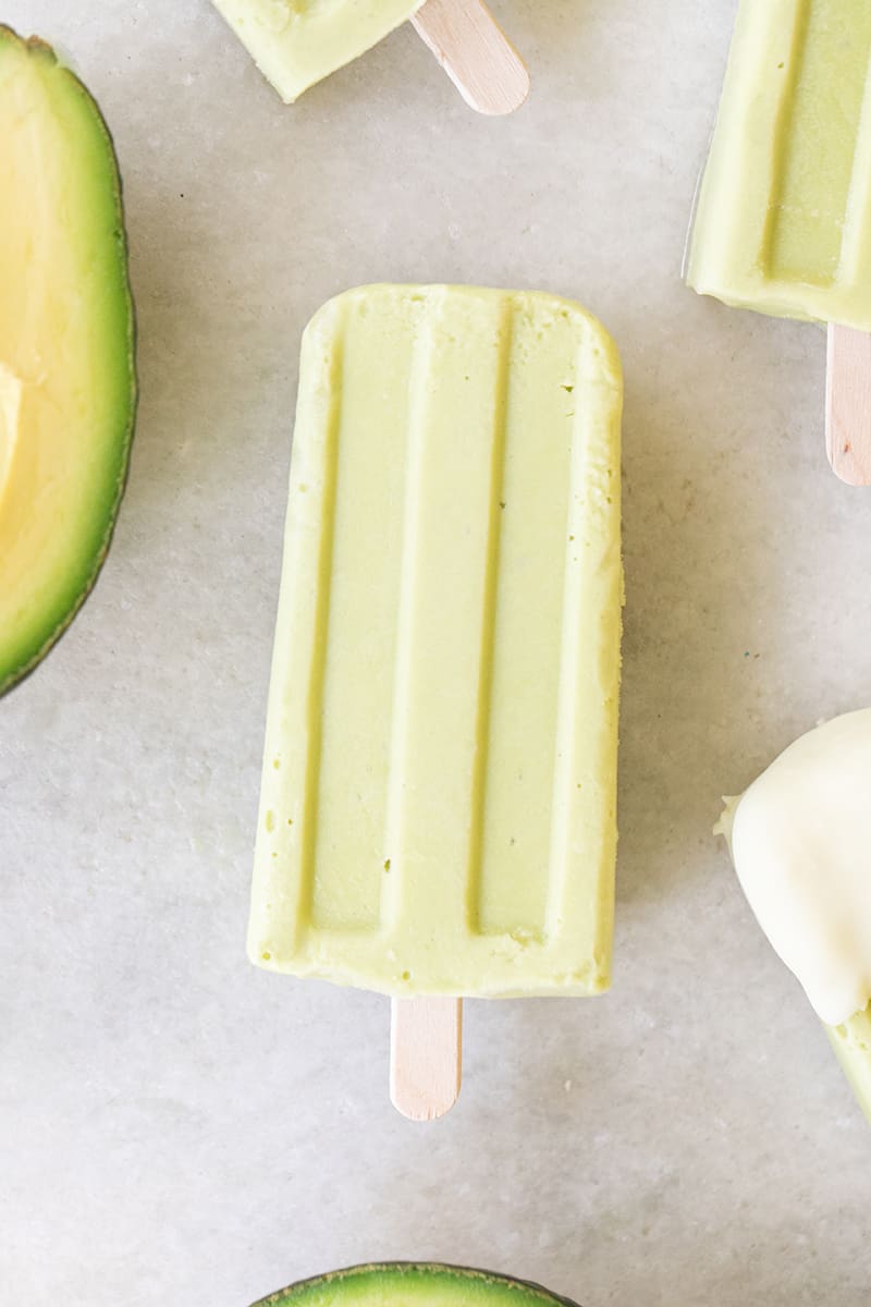 One green avocado popsicle on a marble table. 