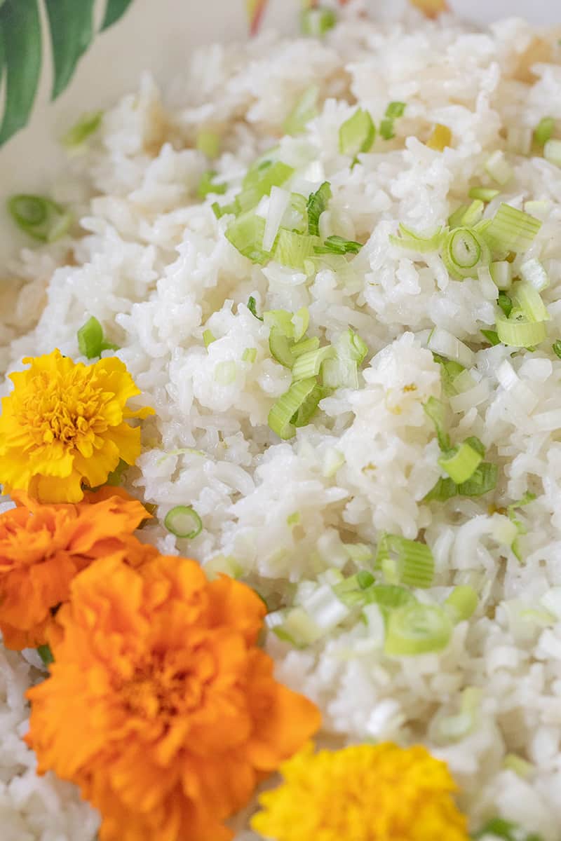 close up of coconut rice with scallions and flowers.