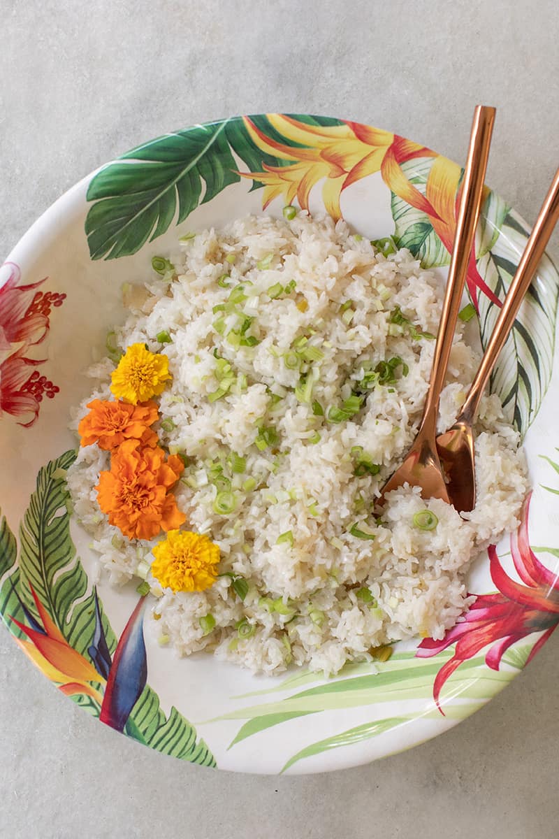 Bowl of coconut rice with copper serving spoons.