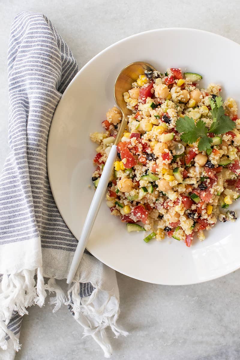 Couscous salad in white bowl on table.