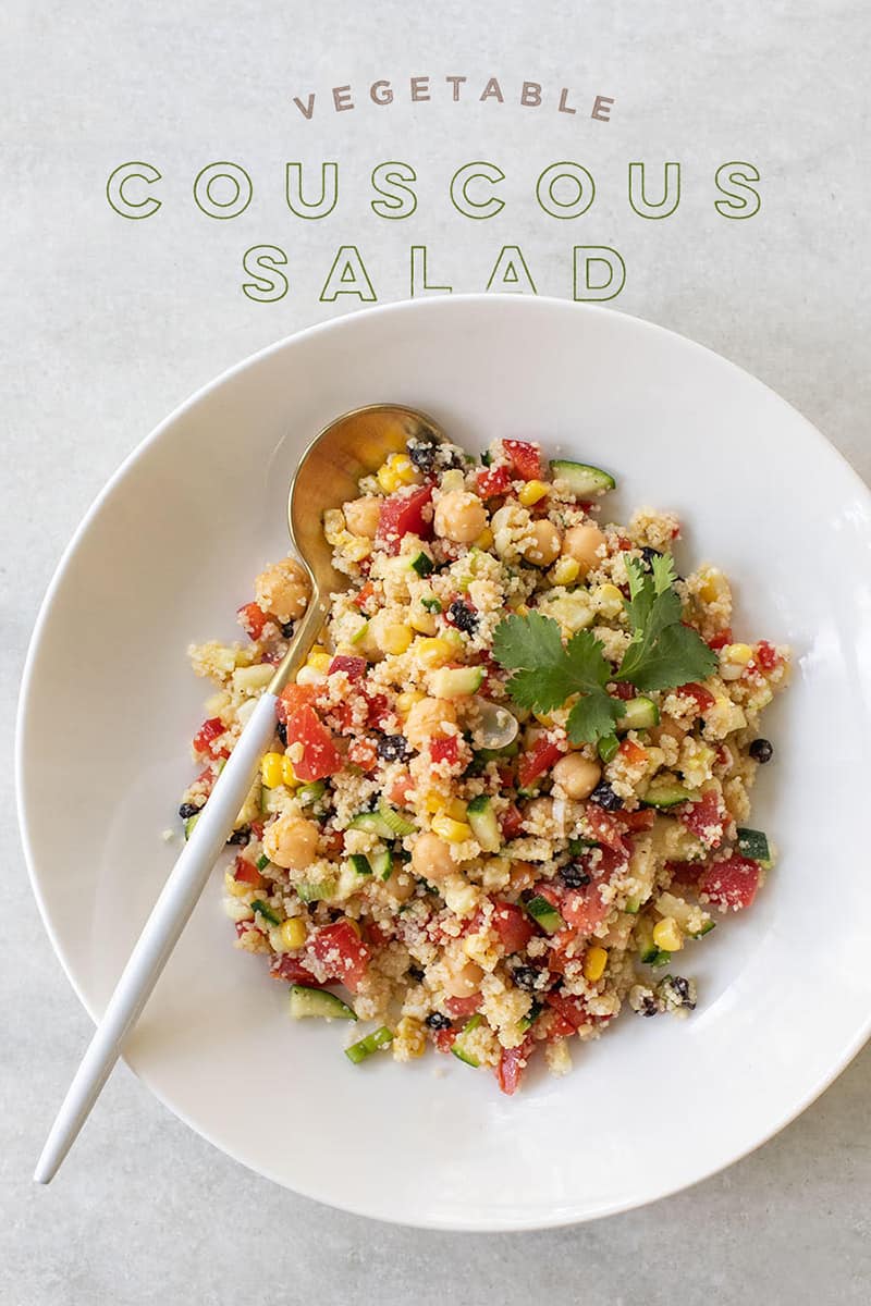 Vegetable couscous in a white bowl with a gold spoon. 