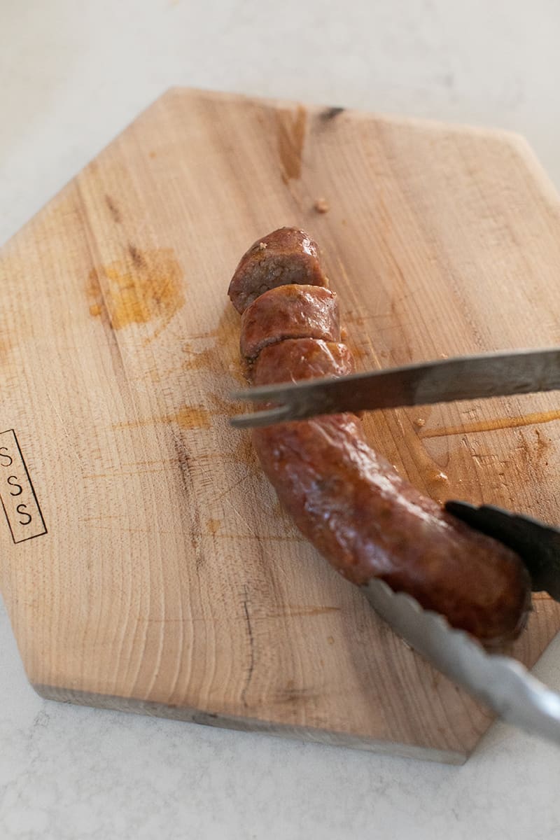 Slicing sausage on a wood cutting board.