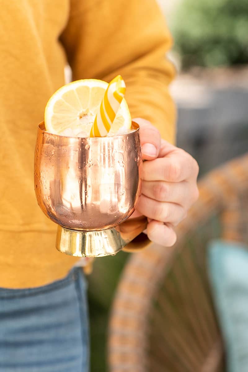 Girl holding a copper mug with a lemon mule inside.