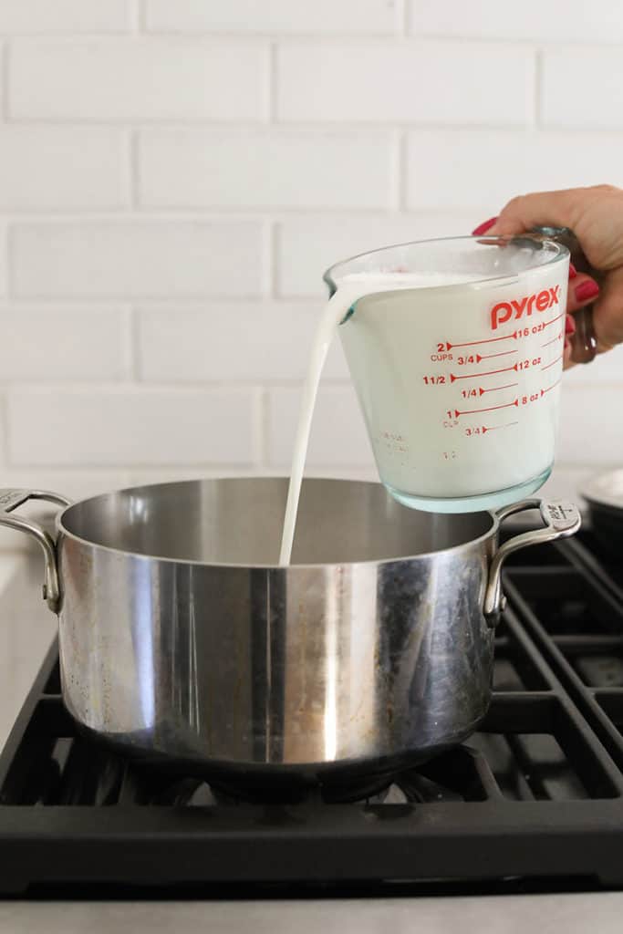 Pouring milk into a pot to make Halloween pudding.