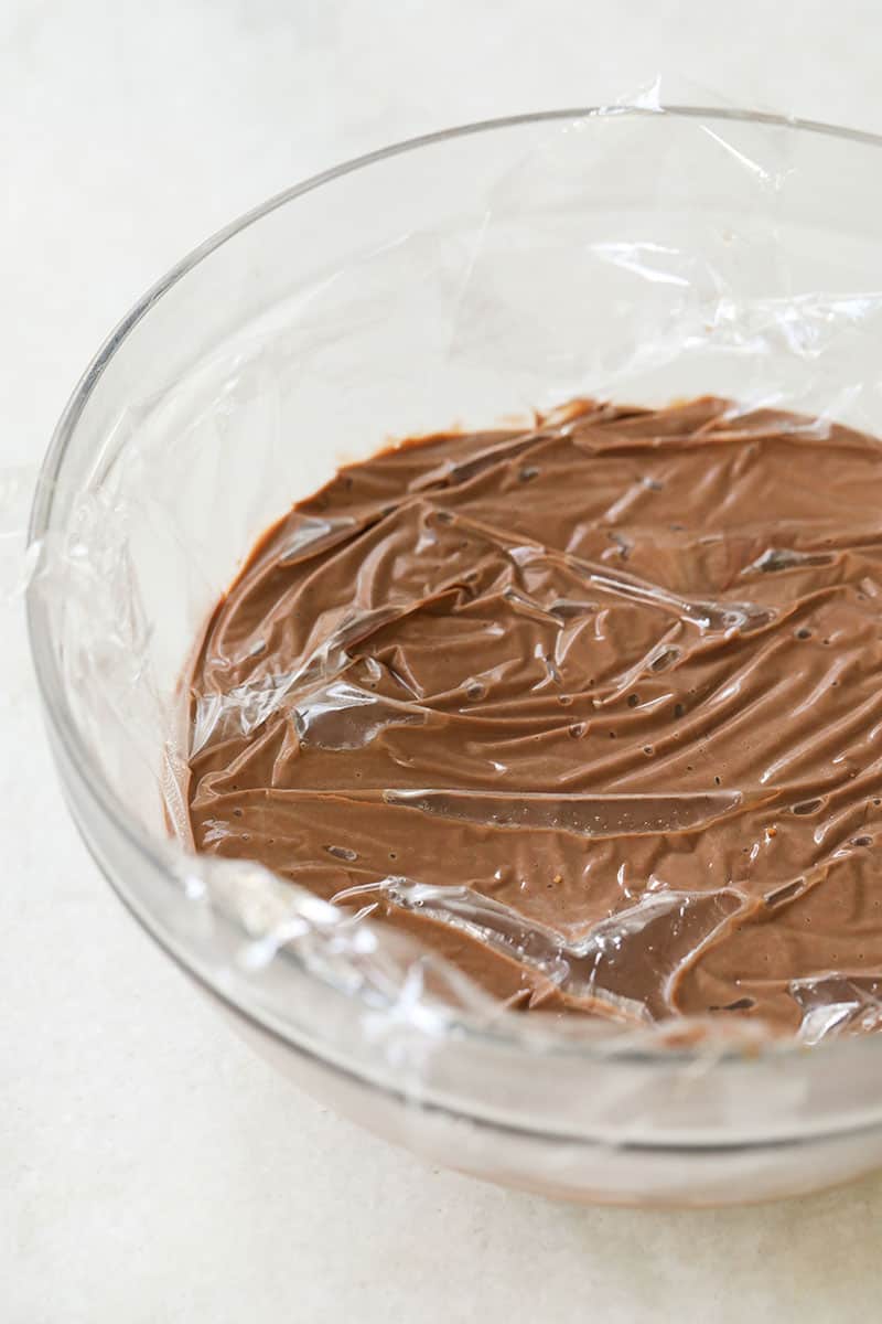 Saran wrap covering chocolate pudding in a glass bowl