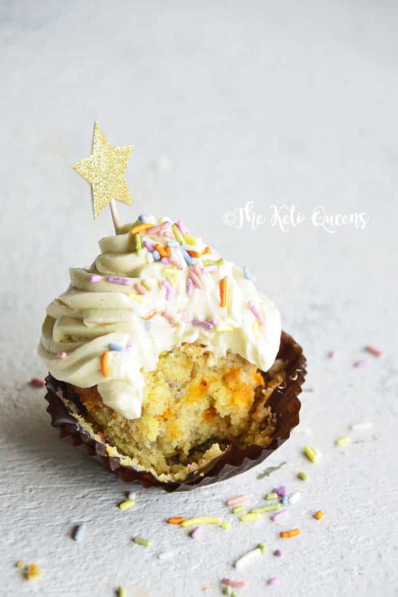 Cute vanilla bean Keto cupcakes with bite taken out and sprinkles on top with a gold star. 