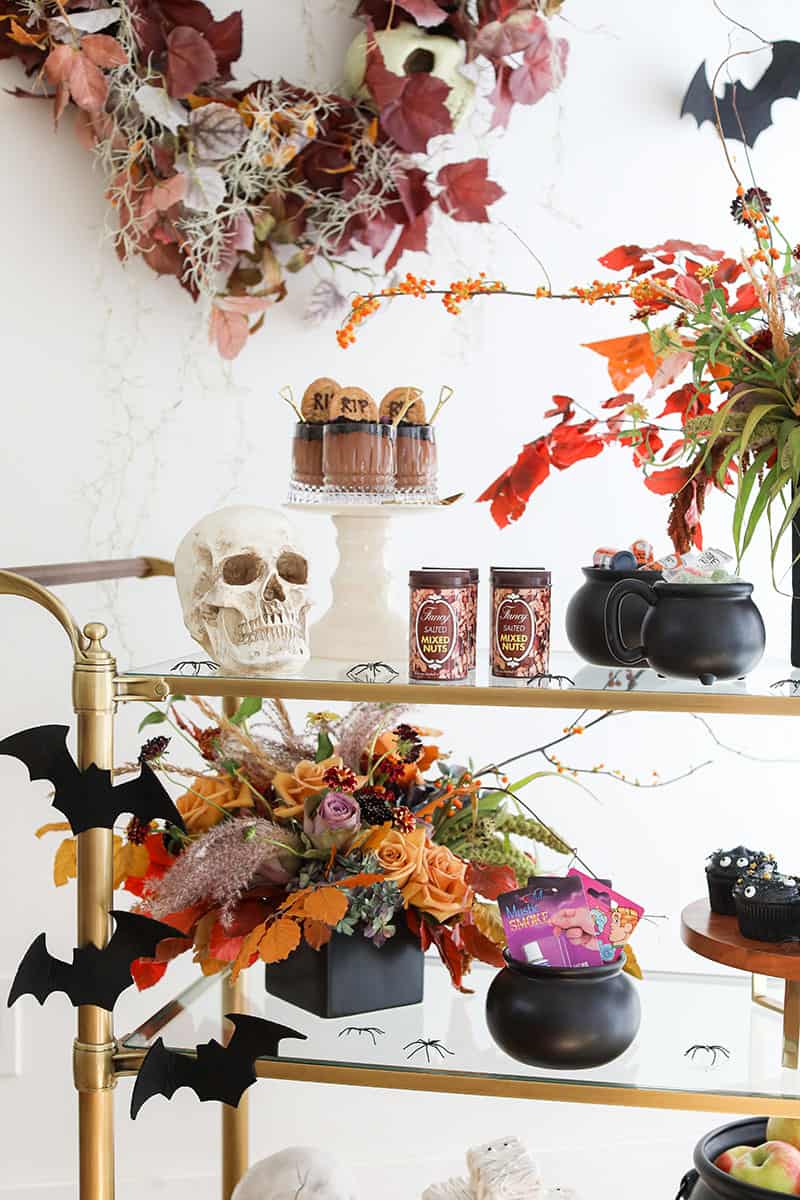 Halloween Party set-up with tricks and treats on a gold bar cart. 