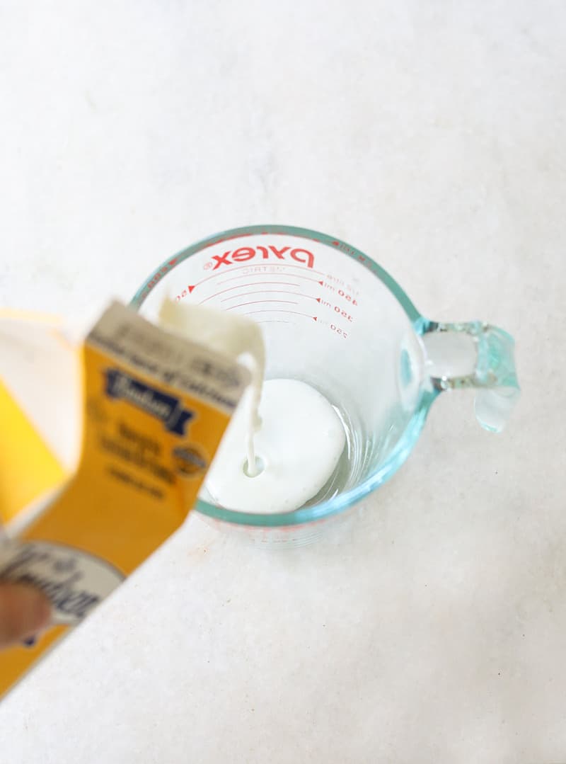 Buttermilk being poured into a glass measuring cup - black cocoa powder