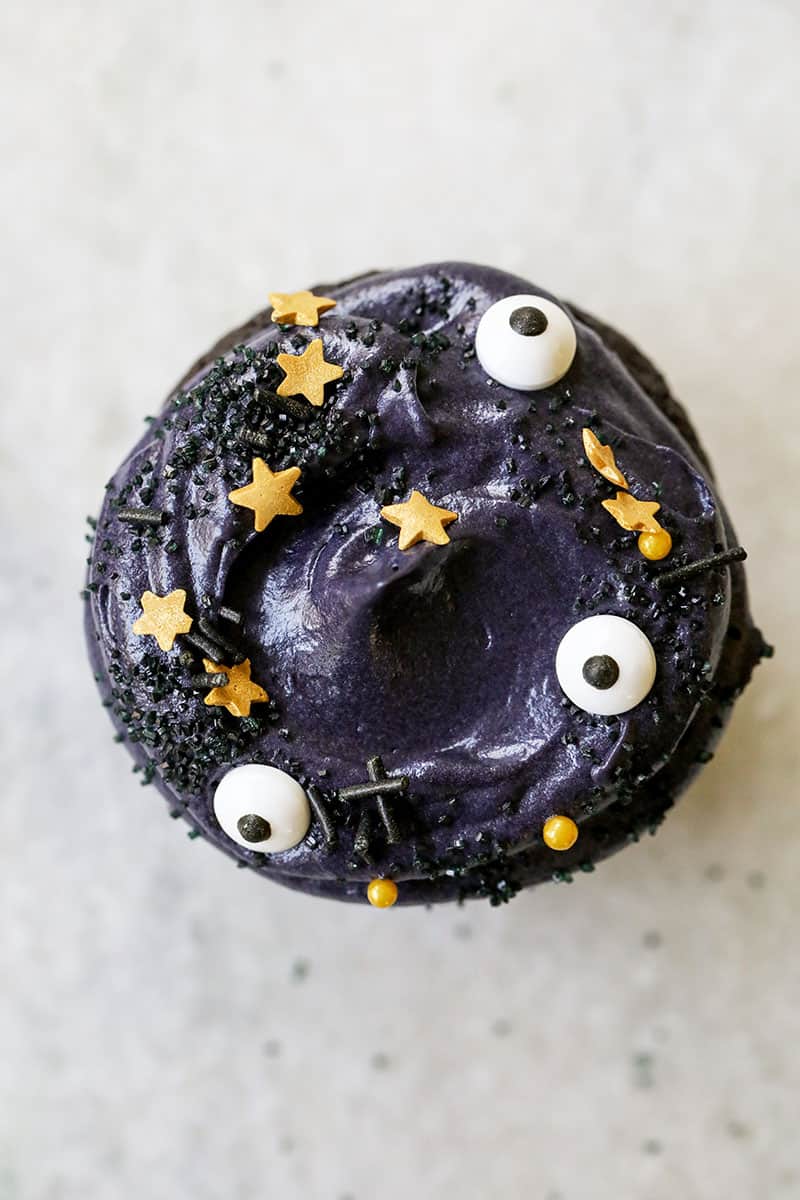 Black velvet cupcake topped with whipped cream cheese frosting and eyeball sprinkles - black cocoa powder