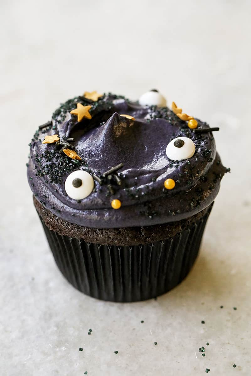 A spooky black velvet cupcake with eyeball sprinkles and gold stars for Halloween - dutch processed cocoa powder