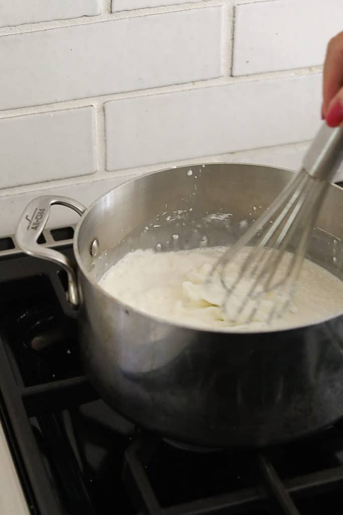 Whisking milk and cream in a saucepan.
