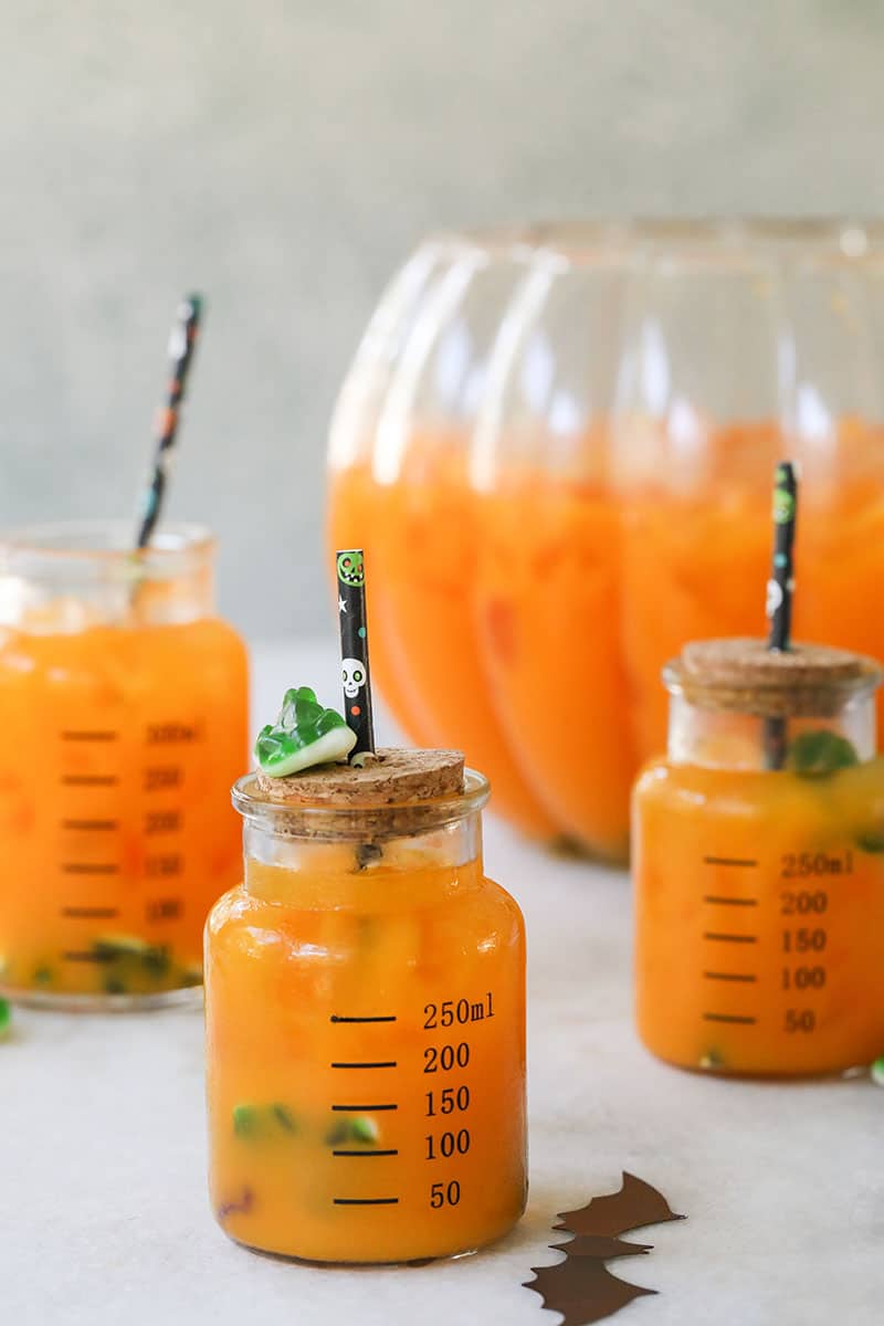 Kids' Halloween punch in a beaker with cork and a Halloween straw.